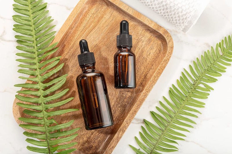 Essential oil bottle on wooden tray. Beauty, skin care, wellness. Yop view