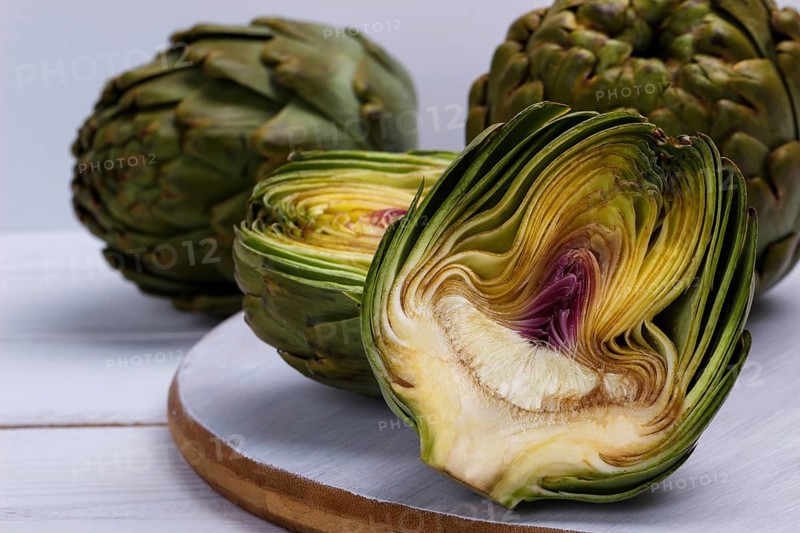 Close up of ripe organic artichokes on rustic wooden board
