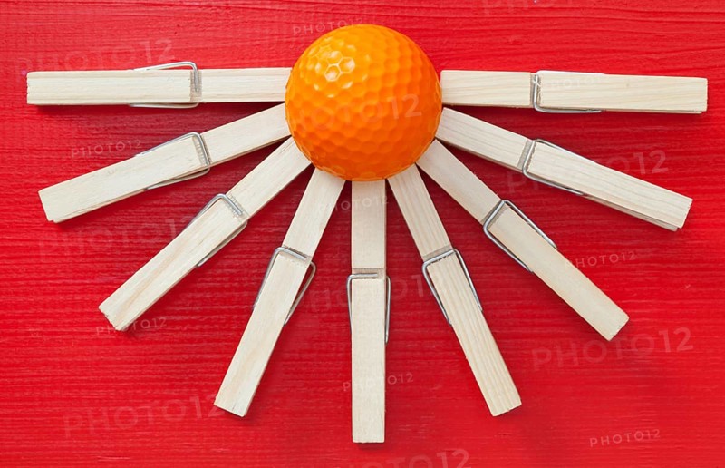 Set of cloth pegs and golf ball on wooden red table