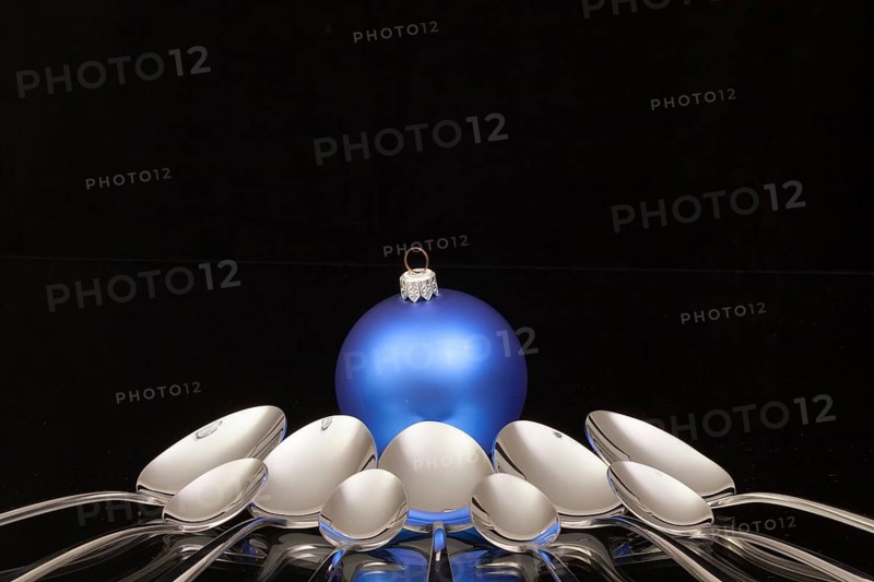 Blue Christmas decoration and nine spoons on a black glass desk
