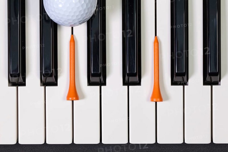 Virtuosic game - Piano keyboard and different golf balls and wooden tees