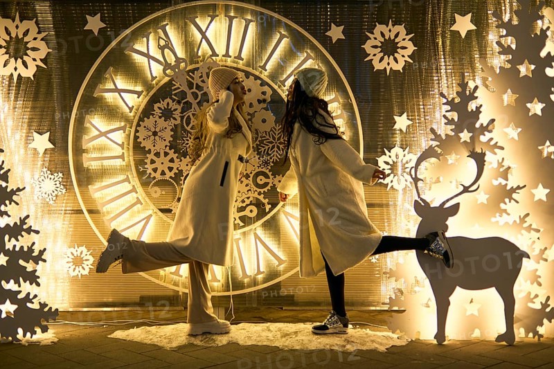 Two girlfriends asian girls in white coats are having fun hugging, new year, light bulbs