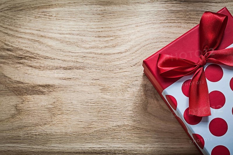 Gift box with red bow on wooden board holidays concept