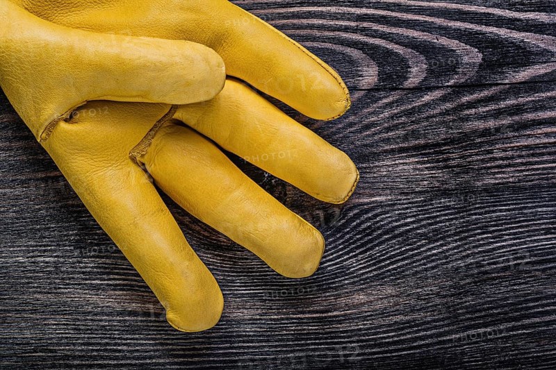 Leather yellow safety glove on vintage wooden board construction concept