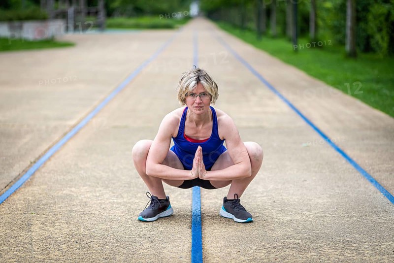 Woman stretching hips and adductors in a squat position, Belgium