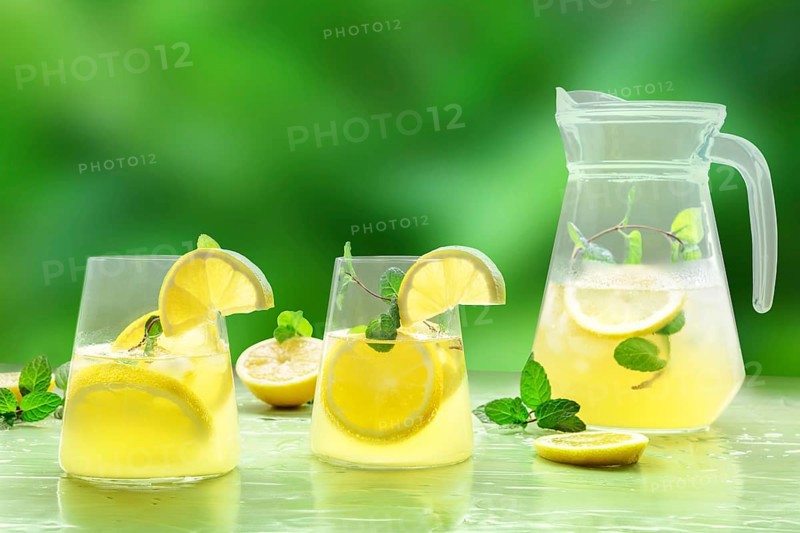 Lemonade with mint on a green background. Lemon water drink with ice. Two glasses and a pitcher. Detox beverage. Fresh homemade cocktail, Food photography, Food photography