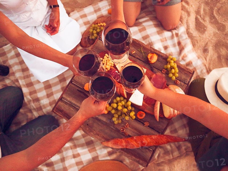 People drinking red wine outdoor. Summer picnic on the beach
