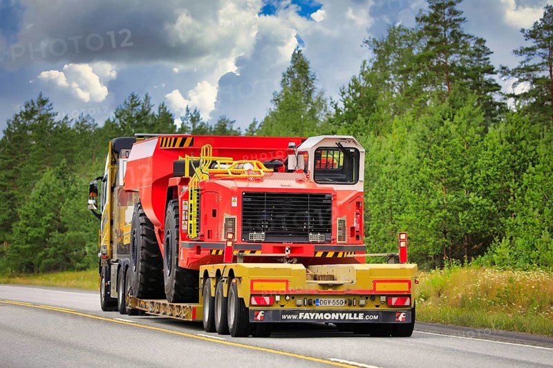Yellow Volvo FH16 semi trailer Mantyla E&E Ky hauls Sandvik underground truck for mining operations on highway 25. Raasepori, Finland. July 24, 2020