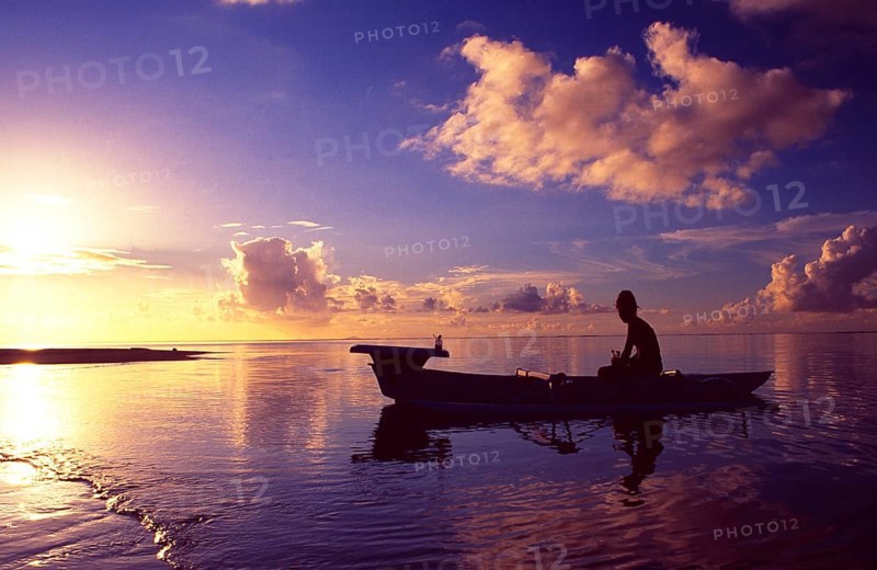 French Polynesia: Woman paddling in a small boat at sunset at Bora Bora Island and Lagoon Resort