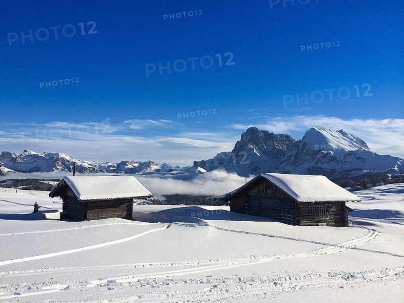 Old wooden barns surrounded by deep snow with skiing tracks in the Dolomites, Italy