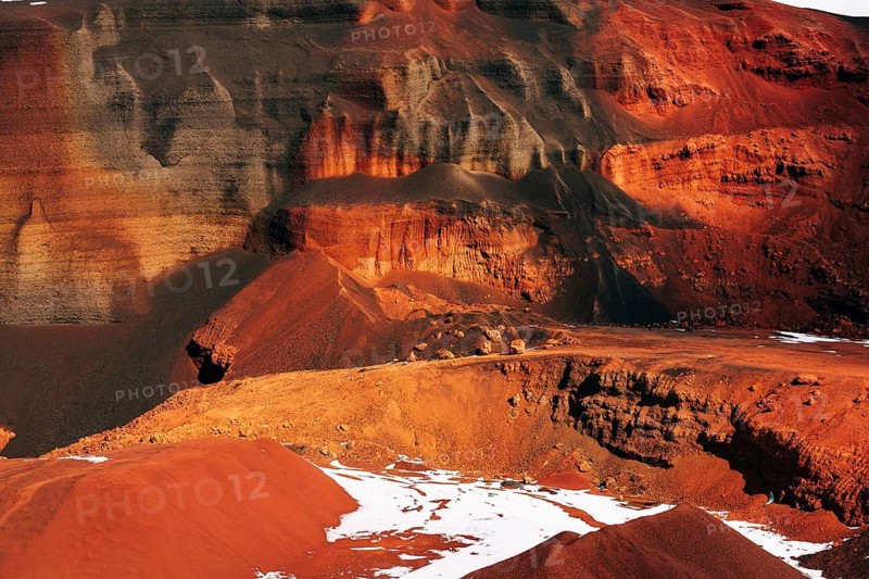 Martian landscapes in Iceland. The red crater of The Seydisholar volcano. The quarry of red soil mining. White snow lies on red soil