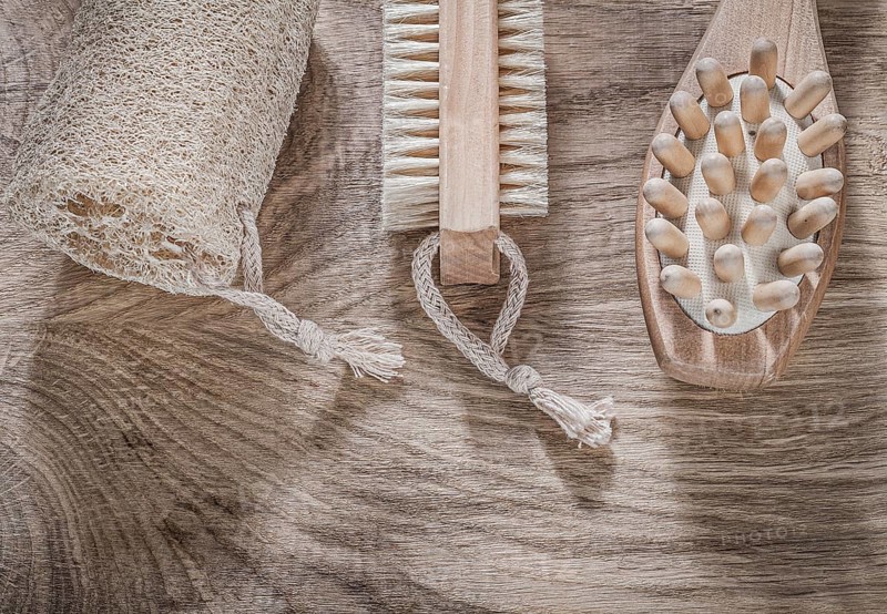 Composition of scrubbing loofah massager bath brush on wooden board spa treatment concept