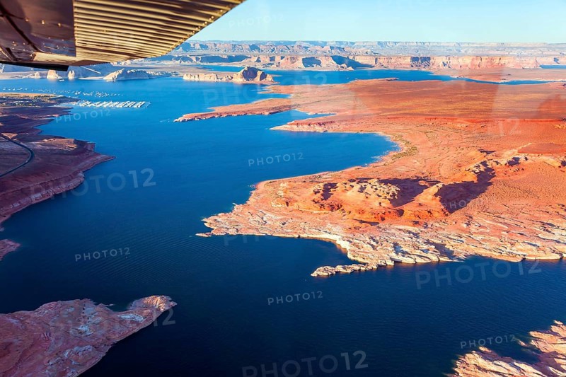 Landscape under the wing of an airplane. Lake Powell is a reservoir on the Colorado River located in the U.S. The blue water of the lake contrast with the red-brown massifs of the rocks