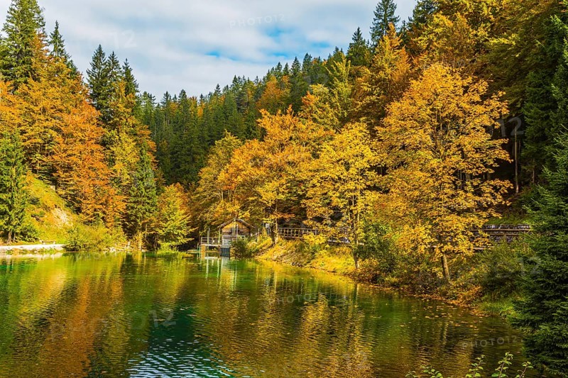 Fantastically beautiful autumn forests are reflected in the quiet lake Lago de Fusine. Easy ripples on the lake. Flood after rain. Concept of cultural and ecological tourism
