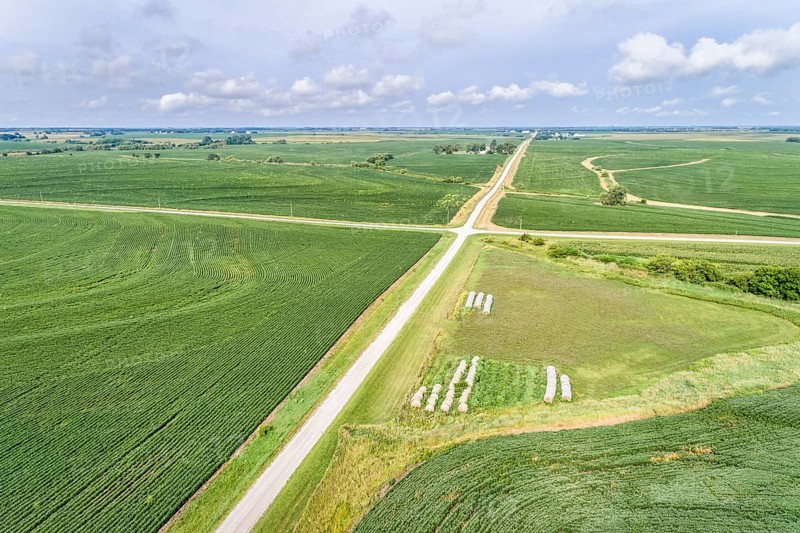 Aerial view of rural Nebraska landscape with a farm road, soybean field and hay bales
