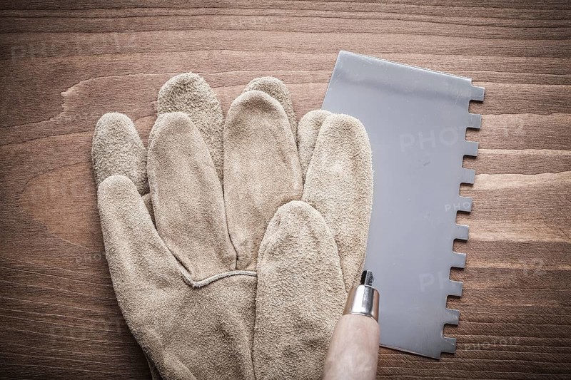 Working glove and putty knife on wood board