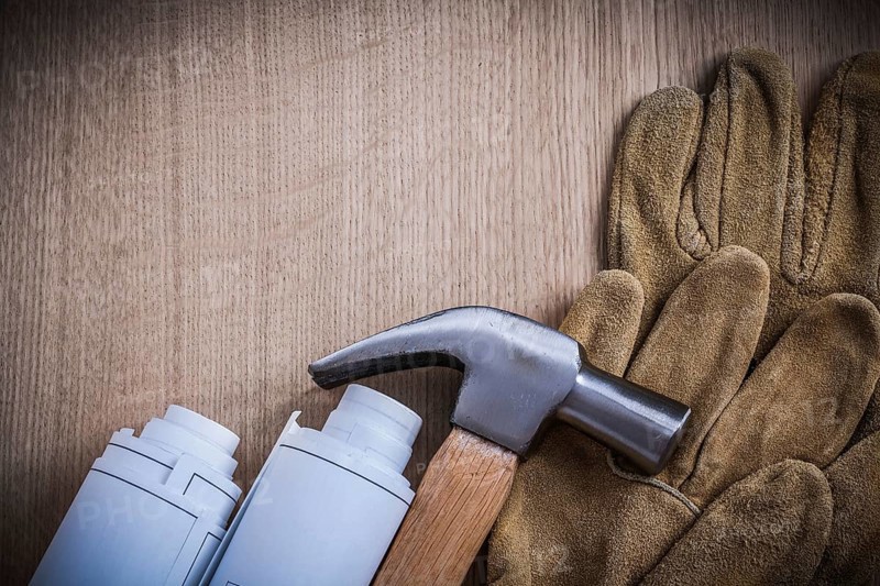 Blueprint rolls safety gloves and claw hammer construction concept