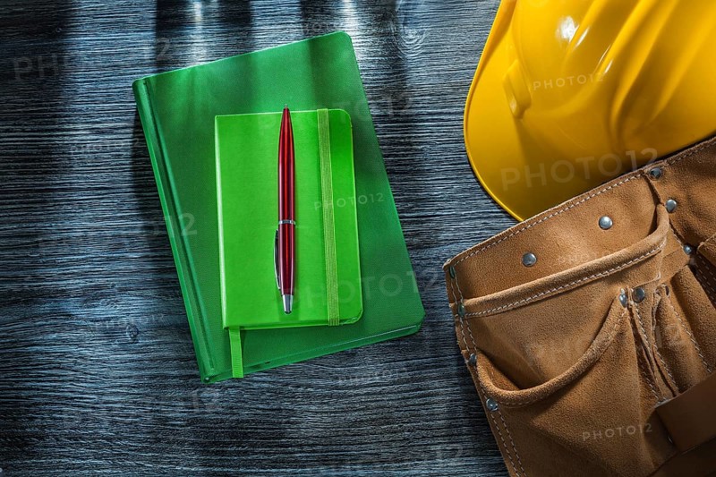 Notepads pen hard hat tool belt on wooden board