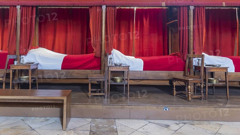 Beaune, France - April 29, 2024: Interior of main room with red beds at Hospices de Beaune or Hotel-Dieu de Beaune a former charitable almshouse in ancient town Beaune in Burgundy region in France