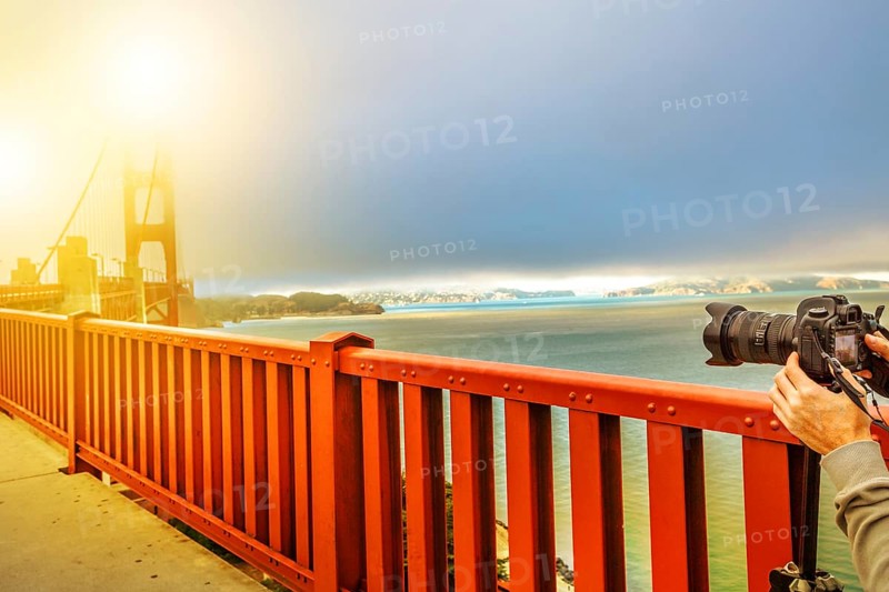 Camera taking a shot of Golden Gate Bridge and red railing, San Francisco, California, United States. Pedestrians perspective of bridge.Concept of hobbies, travel, tourism and professional photography