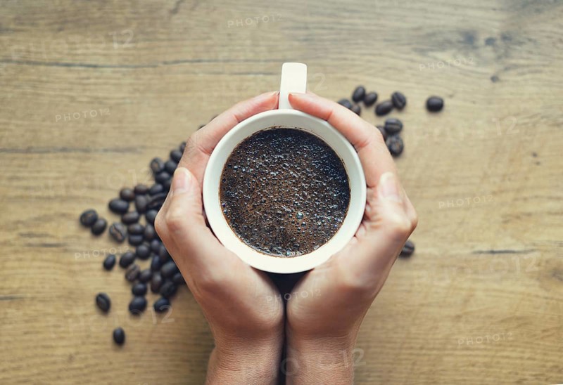 Woman holding cup of freshly brewed coffee
