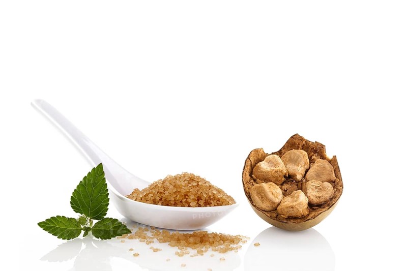Heap of brown cane crystallized sugar in white spoon and monk fruit, luo han guo isolated on white background