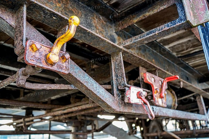 Close-up of rusty wagons with distinctive red levers on a structure, 27568 Bremerhaven