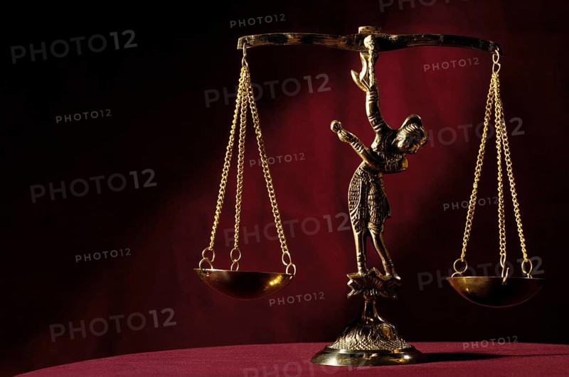 Stock photo of Shiny golden empty balanced vintage justice scales isolated on dark red background Atristic still life conceptual symbol for justice law and attorney