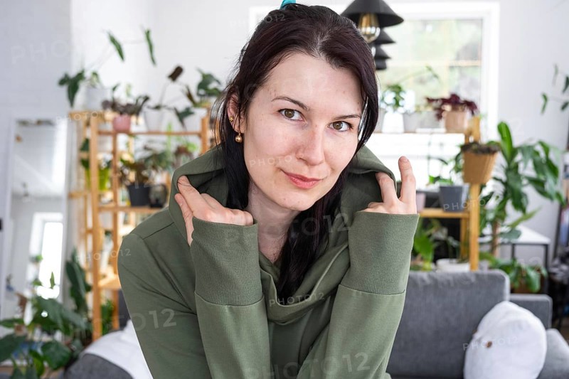 Large portrait Joyful emotions of a woman in the hood in her home in a bright modern interior with home plants. Eco-friendly portrait with real joy