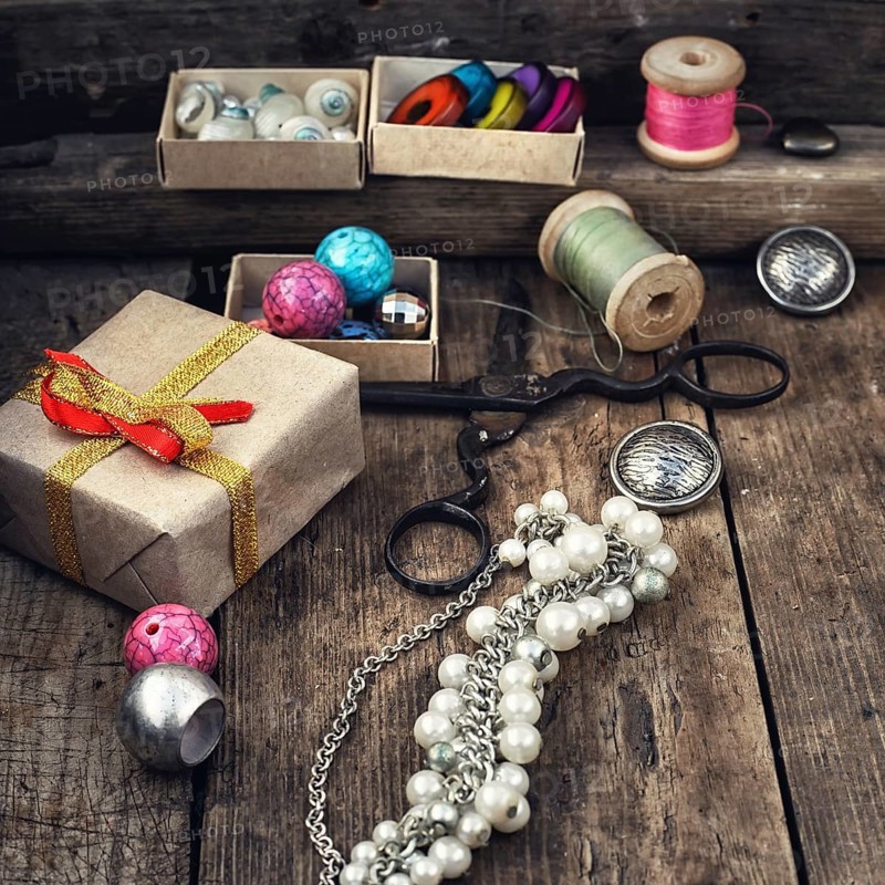 Old scissors, spools of thread, buttons and beads on wooden table