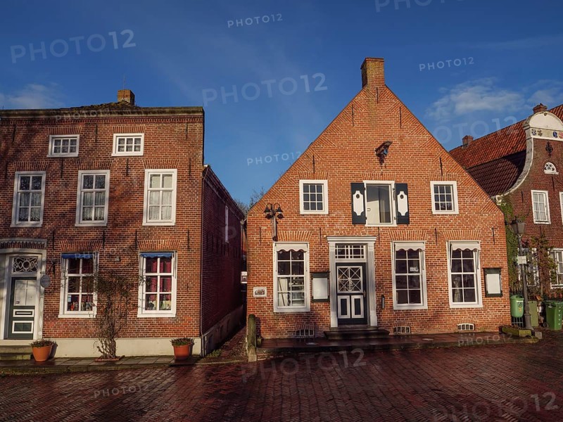 Two brick houses with beautiful façade and balcony under a blue sky, Greetsiel, East Frisia, Germany
