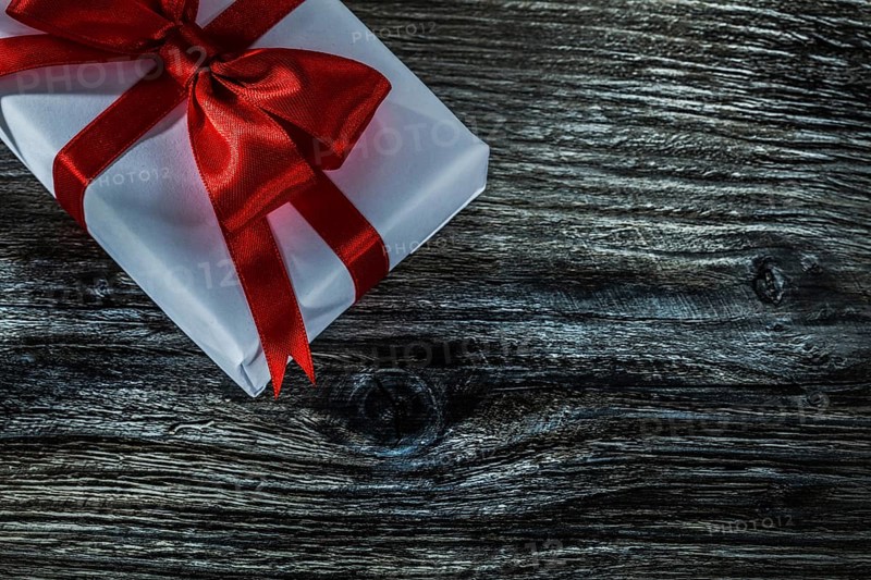 White present box with red bow on wooden board