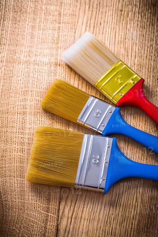Three paint brushes on wooden board construction concept