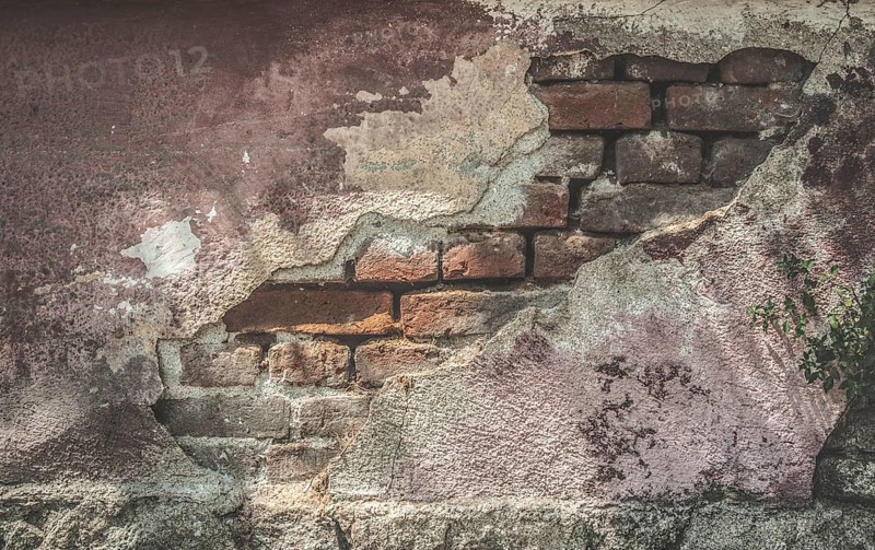 Broken plaster and brick wall. Sunlight