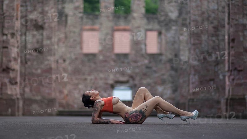 Woman in sporty pose and high heels lying on the ground in front of an old ruin, Staged outdoor shooting, Mindelheim, Unterallgäu, Bavaria, Germany