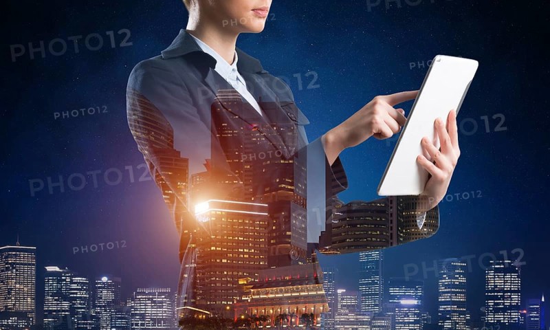 Businesswoman using tablet computer. Double exposure concept with night city and woman in business suit. Real estate investment and development. Digital technology in strategy planning and management