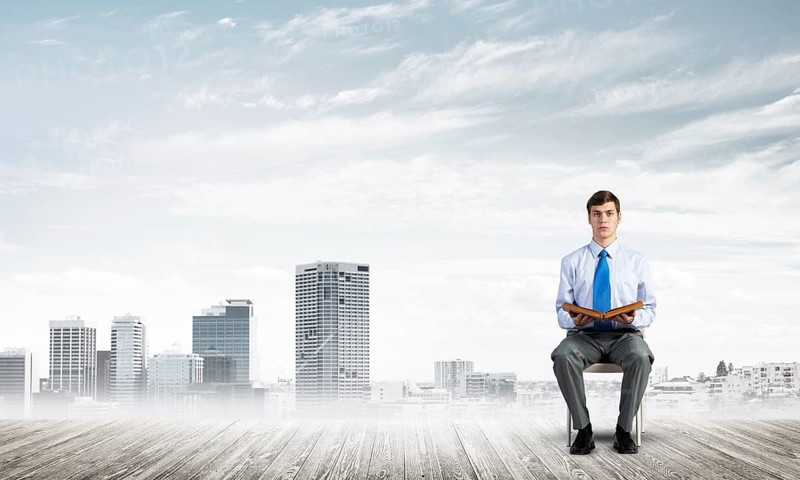 Young businessman with book on office chair