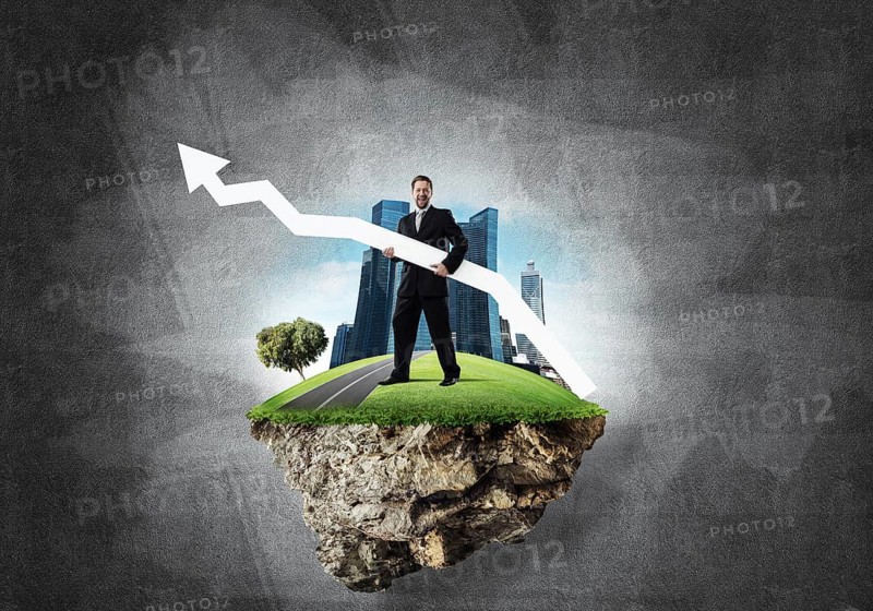 Conceptual image of young and confident business man in suit holding big white arrow in hands