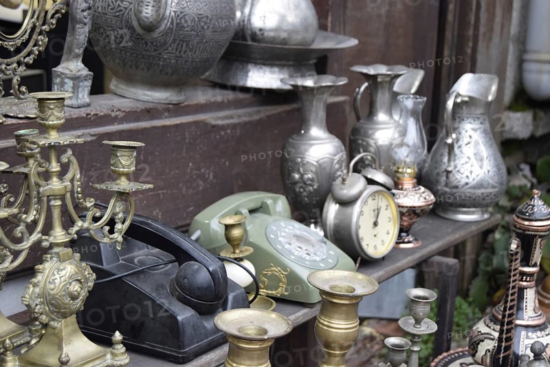A vintage display of metallic jugs, candelabras, old phones, and a clock, Turkey