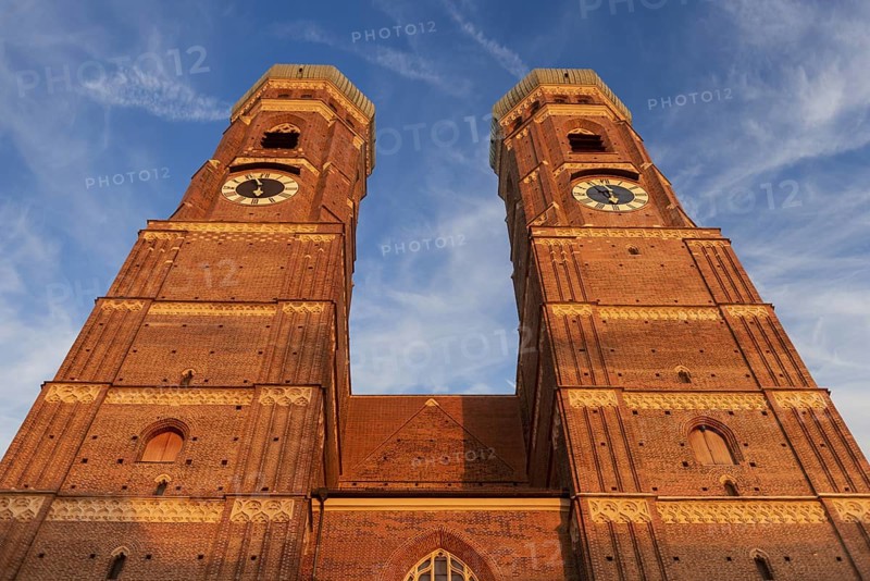 The two towers of the Church of Our Lady in the historic centre of Munich in front of a clear cloud cover with heron clouds and a blue sky in an extreme lower view