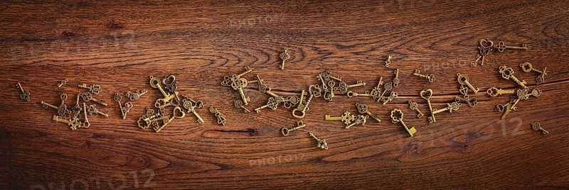 Magical bronze keys on a wooden oak surface in panorama format