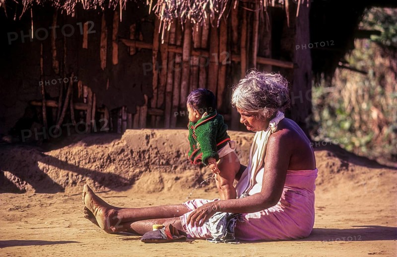 A jenu kurumba tribal old woman with her grandson. Baby urinating in Nagarahole tribal settlement Karnataka, South India, India, Asia