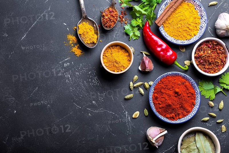 Set of Indian food cooking ingredients. Traditional Indian assorted spices and herbs. Curry, turmeric, cardamom, garlic, pepper, cilantro, cinnamon. Preparing exotic meal. Top view, close up