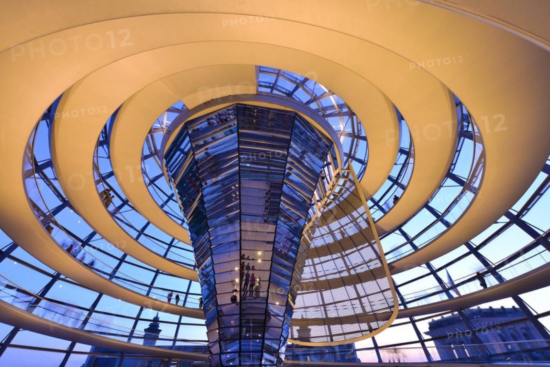 Reichstag in Berlin, the photo shows the dome of the Reichstag with the walkable spiral inside. The architect Norman Foster designed the dome. The glass dome provides the plenum with natural daylight and serves as ventilation. Reichstag building in Berlin. The large glass dome at the very top of the Reichstag has a 360-degree view of the surrounding Berlin cityscape. The main hall of the parliament below can also be seen from inside the dome, and natural light from above radiates down