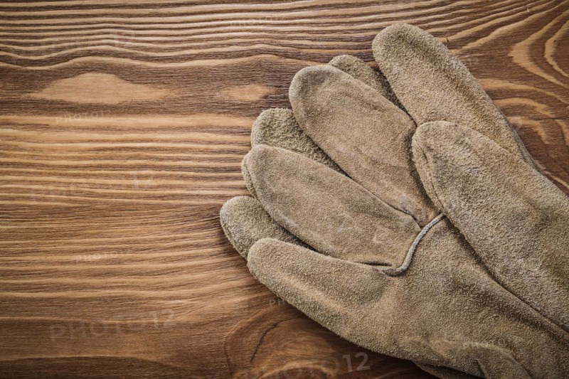 Brown protective gloves on vintage wooden board Construction concept
