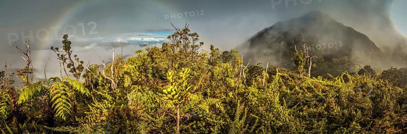 Panoramic photo of mountains covered by fog with rainbow in Digne in Kubor range, Papua New Guinea. In this region, one can only meet people from isolated local tribes