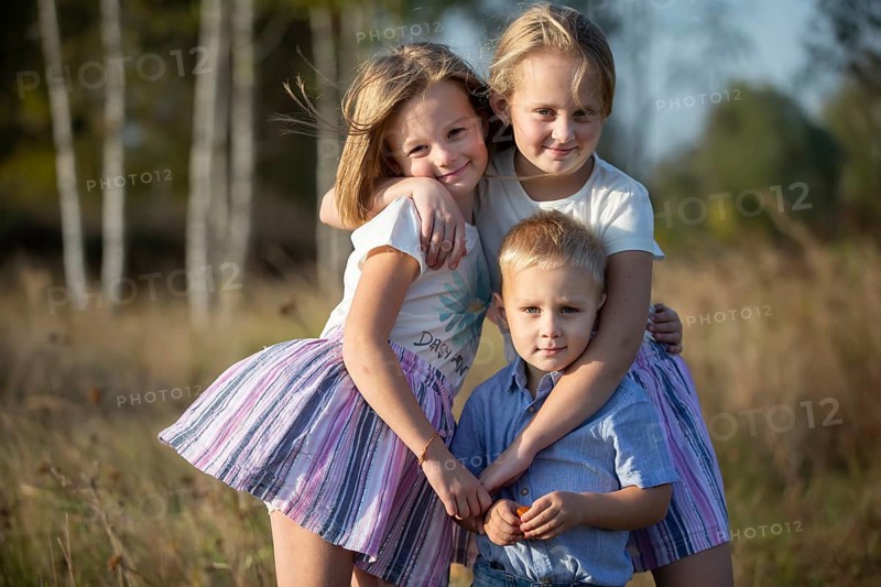 Little brother and two sisters are looking at the camera