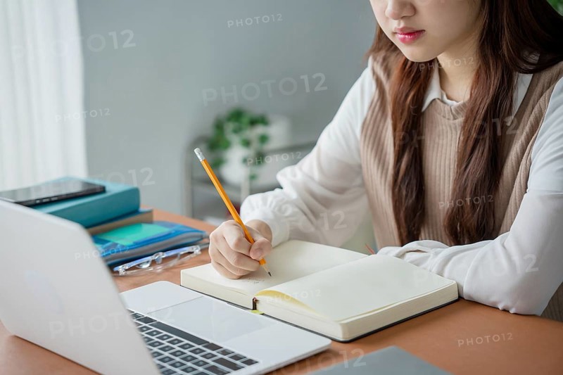 Asian woman using laptop to study student engaged in online learning at college