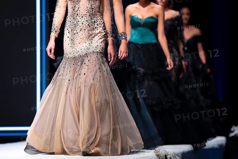 Female models walk the runway in beautiful designer dresses during a Fashion Show. Fashion catwalk event showing new collection of clothes. Unrecognizable people