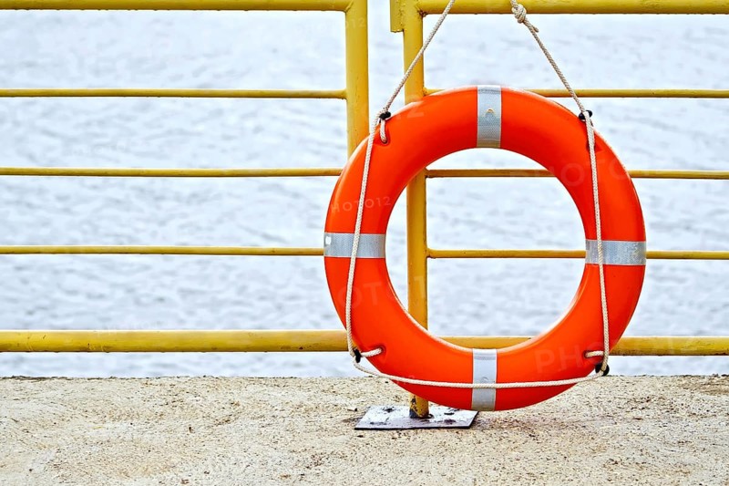 Lifebuoys red hanging on the yellow fence on the background of water